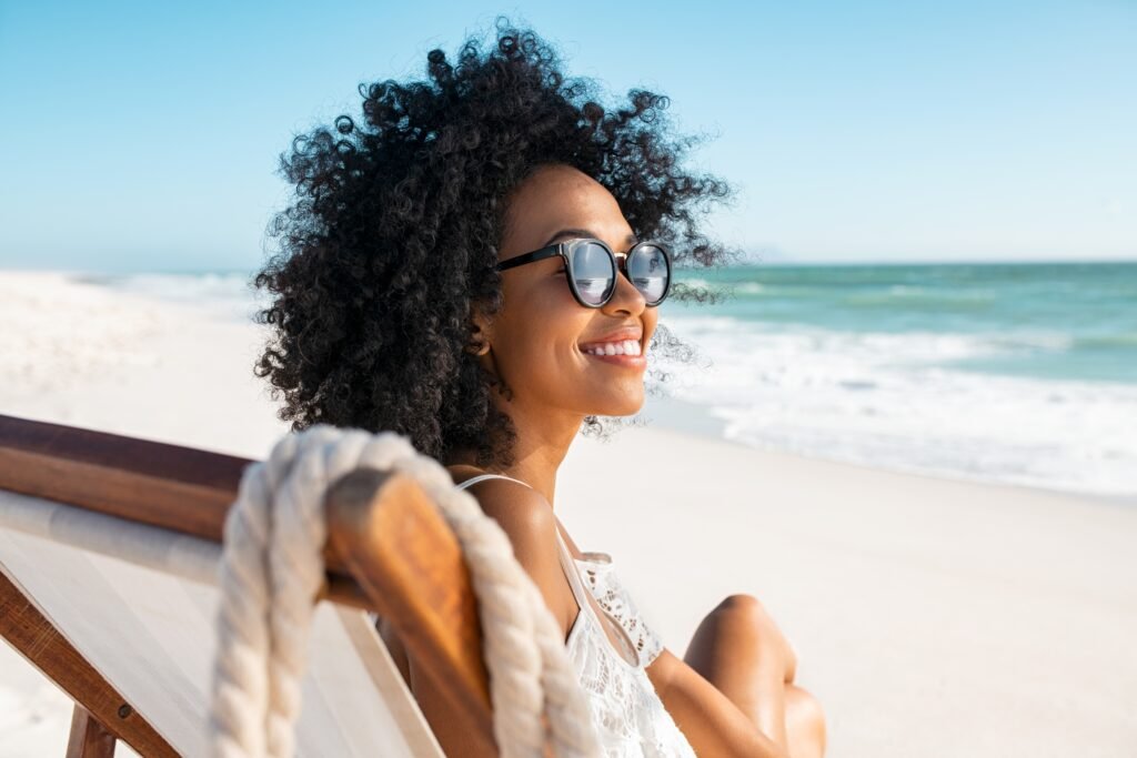 happy,young,black,woman,relaxing,on,deck,chair,at,beach